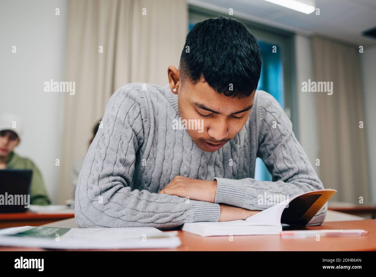 Teenager Junge Buch lesen, während das Studium an der Tischschule Stockfoto