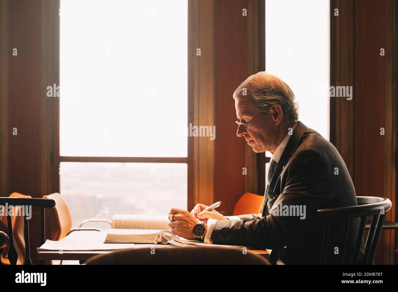 Seitenansicht der reifen Anwalt Recherche beim Lesen von Büchern an Büro Stockfoto