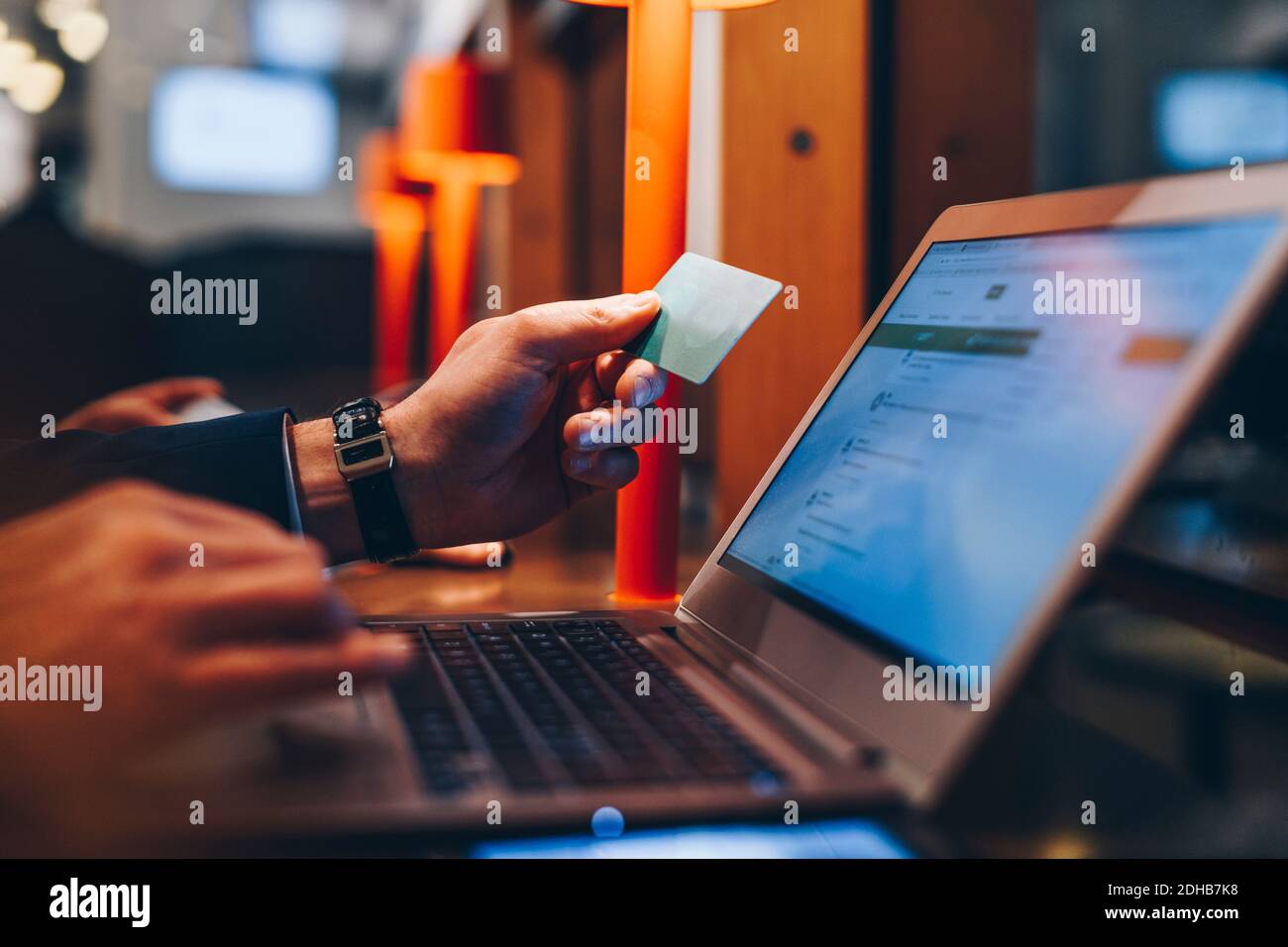 Zugeschnittenes Bild des Geschäftsmannes, der während der Verwendung eines Laptops eine Kreditkarte hält Am Flughafen Stockfoto