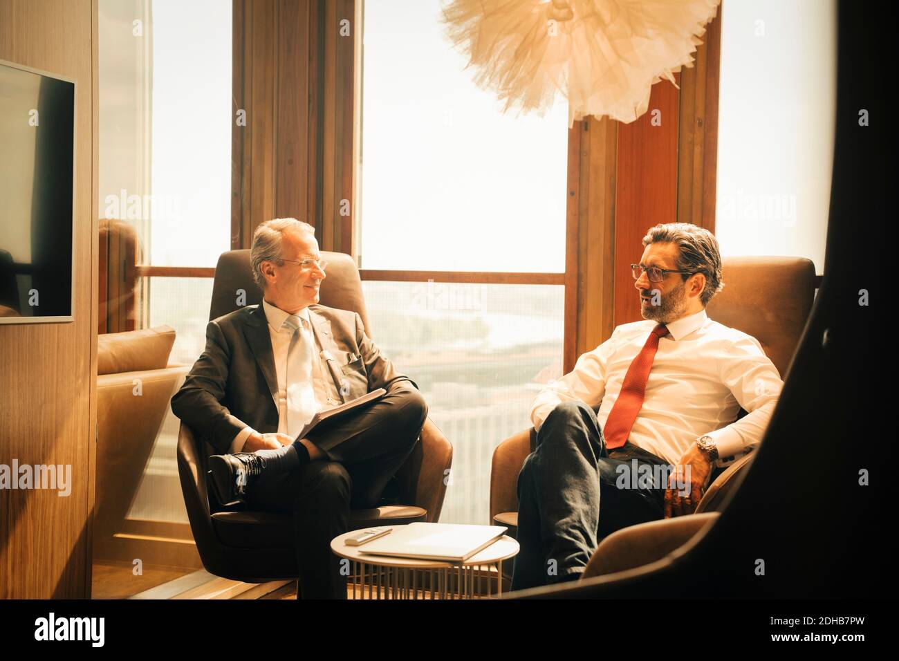 Männliche Anwälte planen, während sitzen gegen Fenster bei Anwaltskanzlei Stockfoto