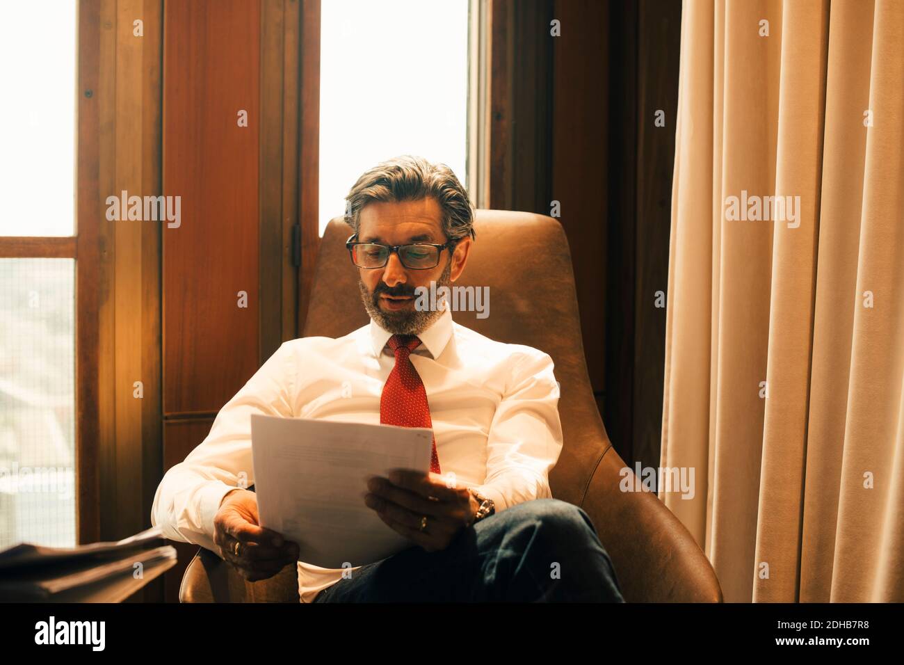 Männlicher Finanzberater beim Lesen von Dokumenten in der Anwaltskanzlei Stockfoto