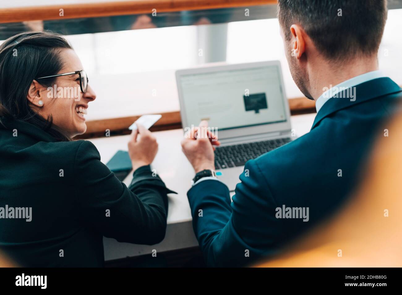 Glückliche Geschäftsfrau mit Kreditkarte, während Geschäftsmann mit Laptop in flughafen Stockfoto