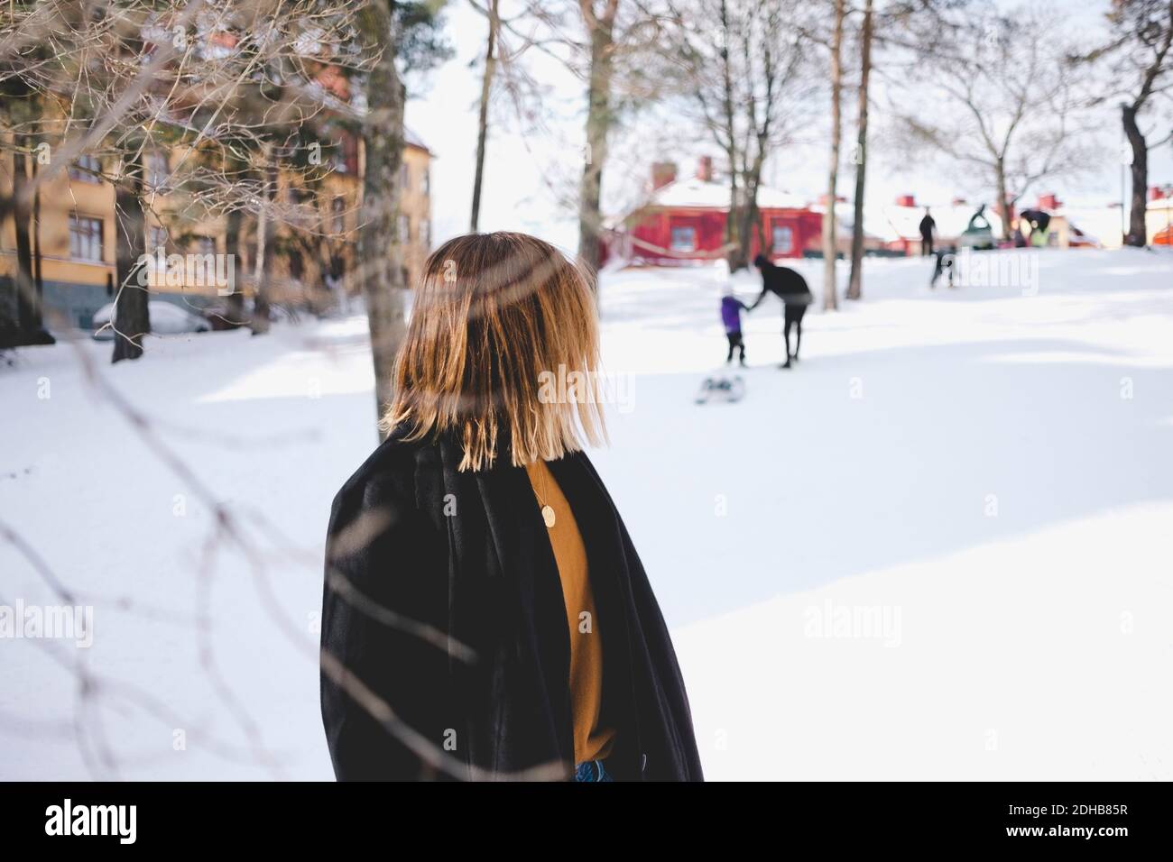 Junge Frau, die über die Schulter schaut, während sie auf Schnee steht Land Stockfoto