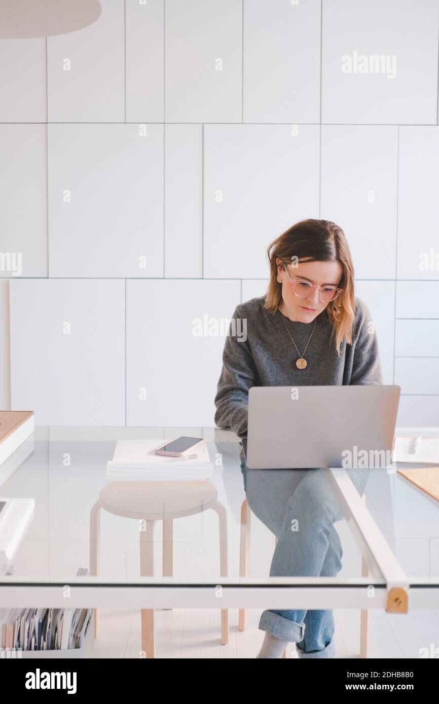 Junge Unternehmerin mit Laptop am Schreibtisch im Designstudio Stockfoto