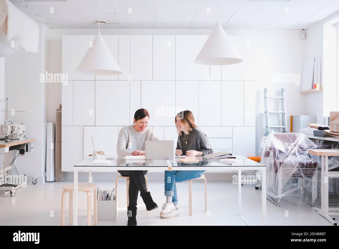 Lächelnde Modedesignerinnen diskutieren über Laptop am Schreibtisch studio Stockfoto