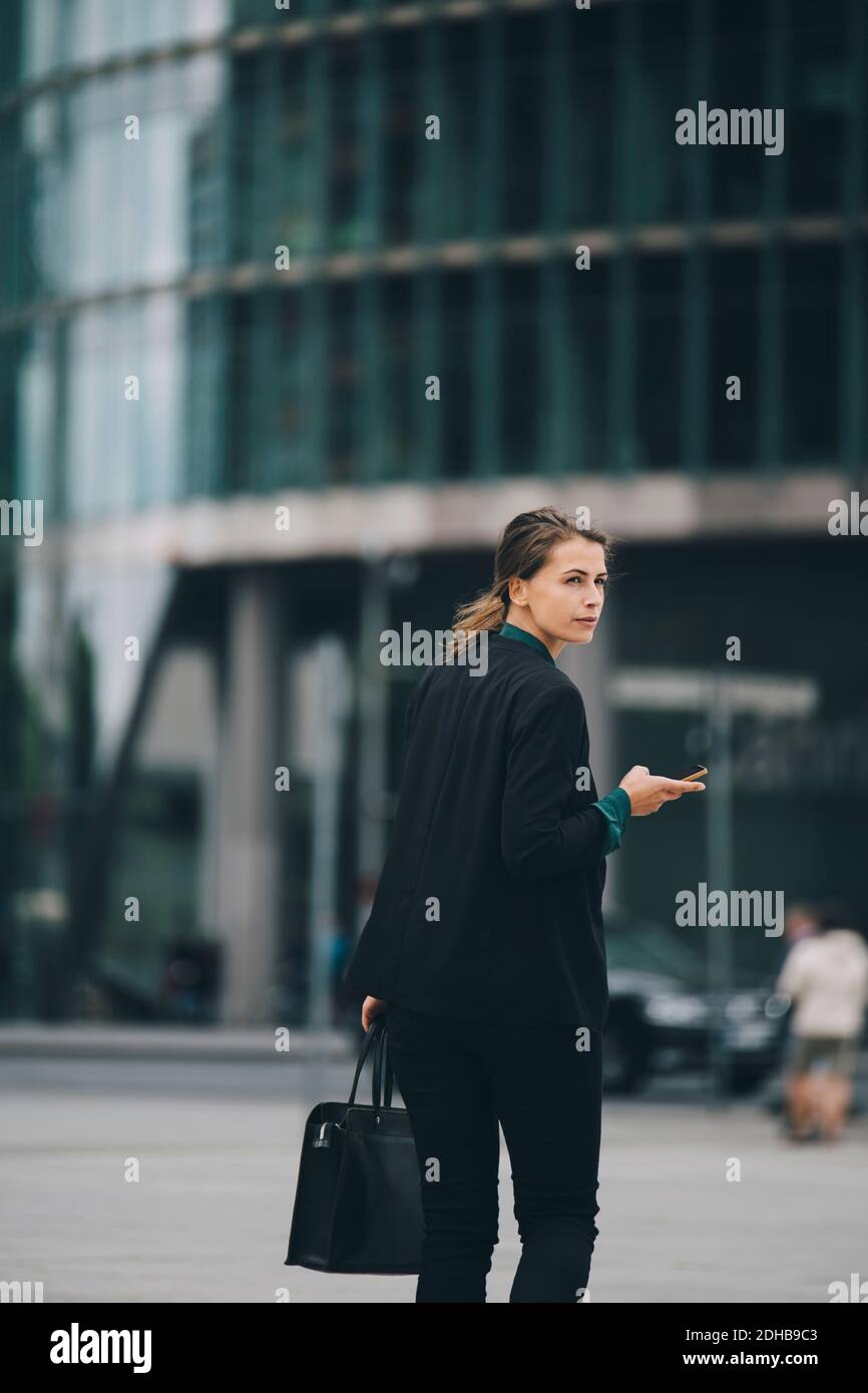 Geschäftsfrau, die über die Schulter schaut, während sie auf der Straße in der Stadt läuft Stockfoto