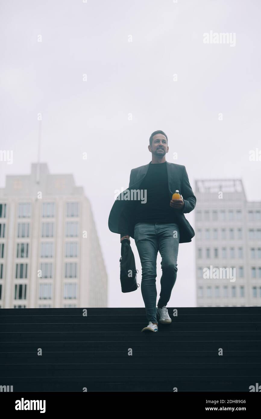 Geschäftsmann, der auf Stufen in der U-Bahn gegen den klaren Himmel geht Stockfoto