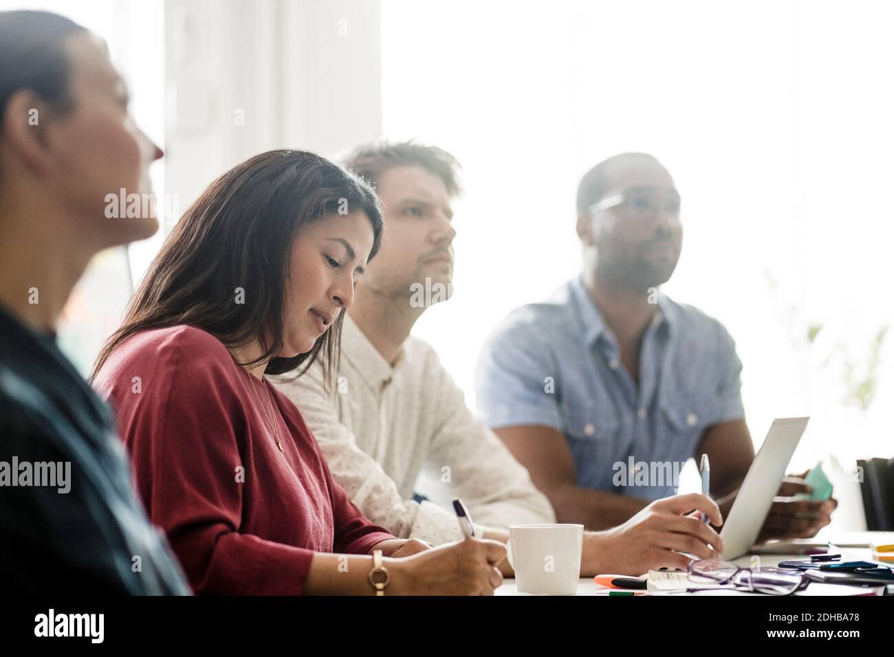 Männliche und weibliche Mitarbeiter hören Geschäftsplan in der Sitzung bei Konferenzraum Stockfoto