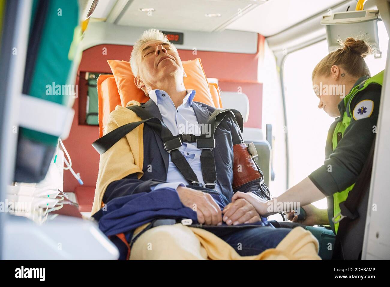 Weibliche Sanitäterin, die den Blutdruck des Mannes im Krankenwagen überprüft Stockfoto