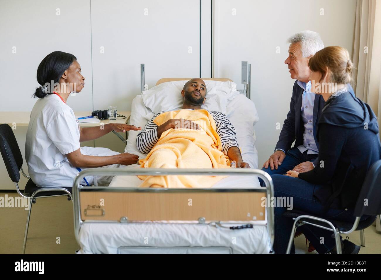Junger Mann, der die Familie ansieht, während der Arzt im Krankenhaus diskutiert Station Stockfoto
