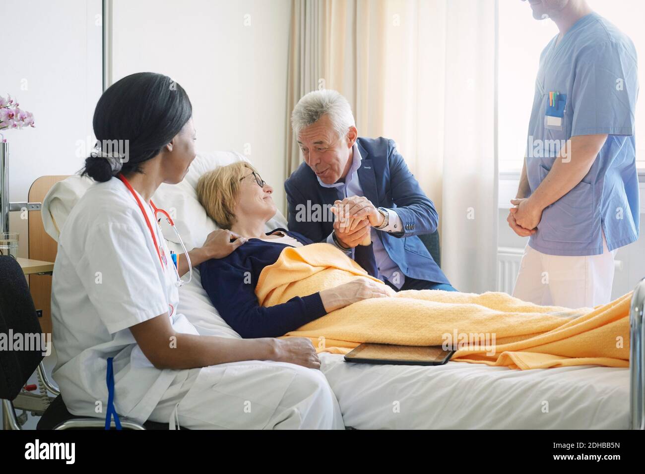 Gesundheitshelfer, die einen älteren Mann betrachten, der den Patienten im Krankenhaus tröstet Station Stockfoto