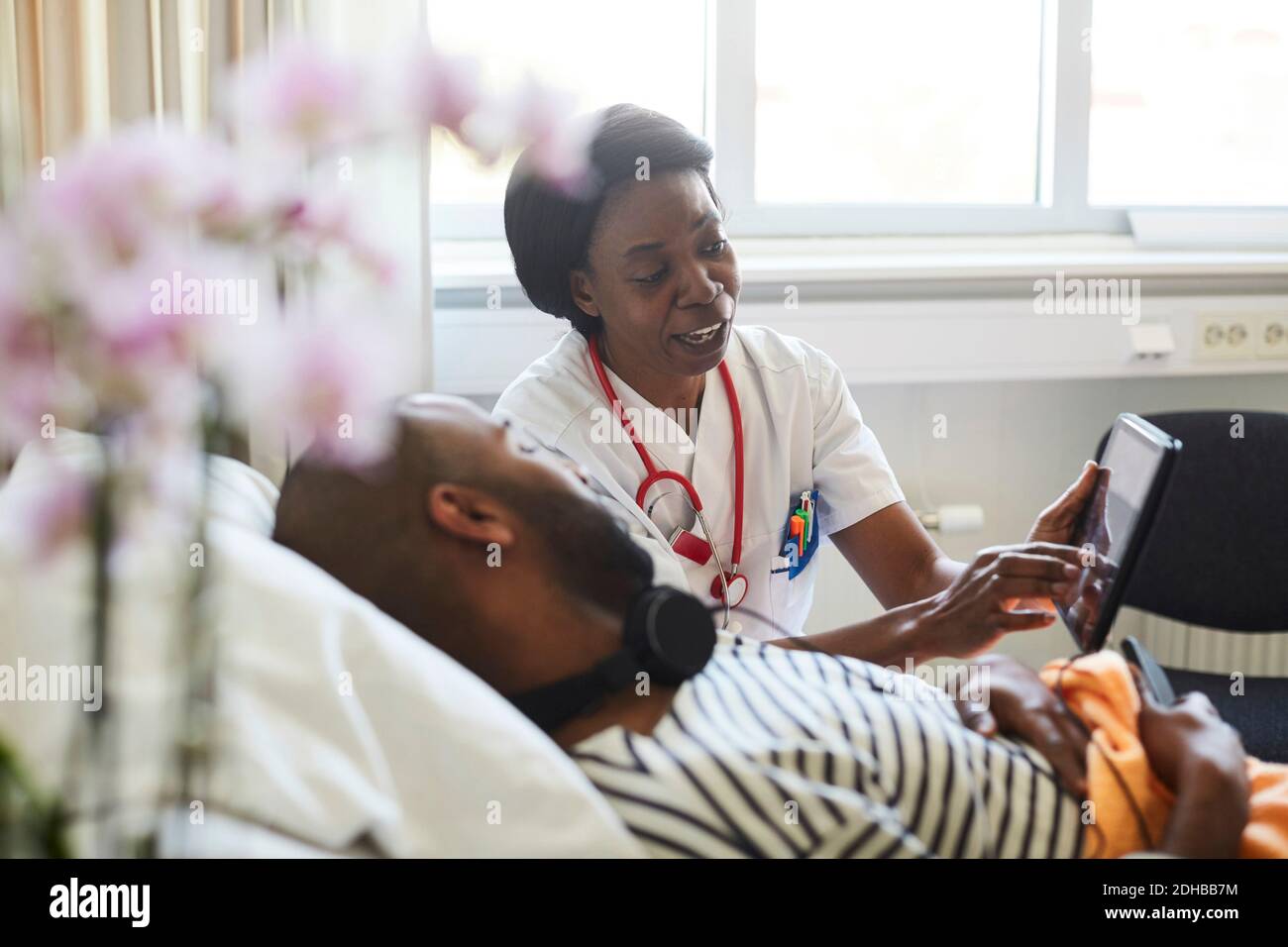Reifer Arzt zeigt digitale Tablette zu männlichen Patienten während der Routine Besuch im Krankenhaus Stockfoto