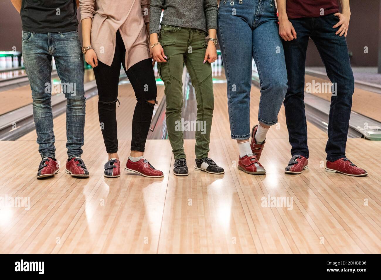 Niedriger Teil der multi-ethnischen Freunde stehen auf Parkettboden bei Bowlingbahn Stockfoto