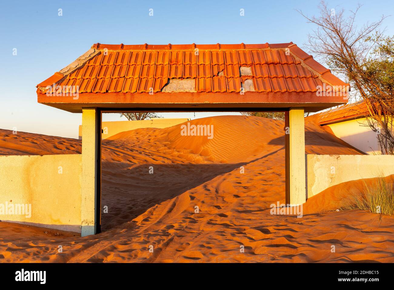 Mauer und gefliestes Tor in Sanddünen in der Wüste in Al Madam Geisterdorf, Vereinigte Arabische Emirate begraben, Sonnenuntergang. Stockfoto