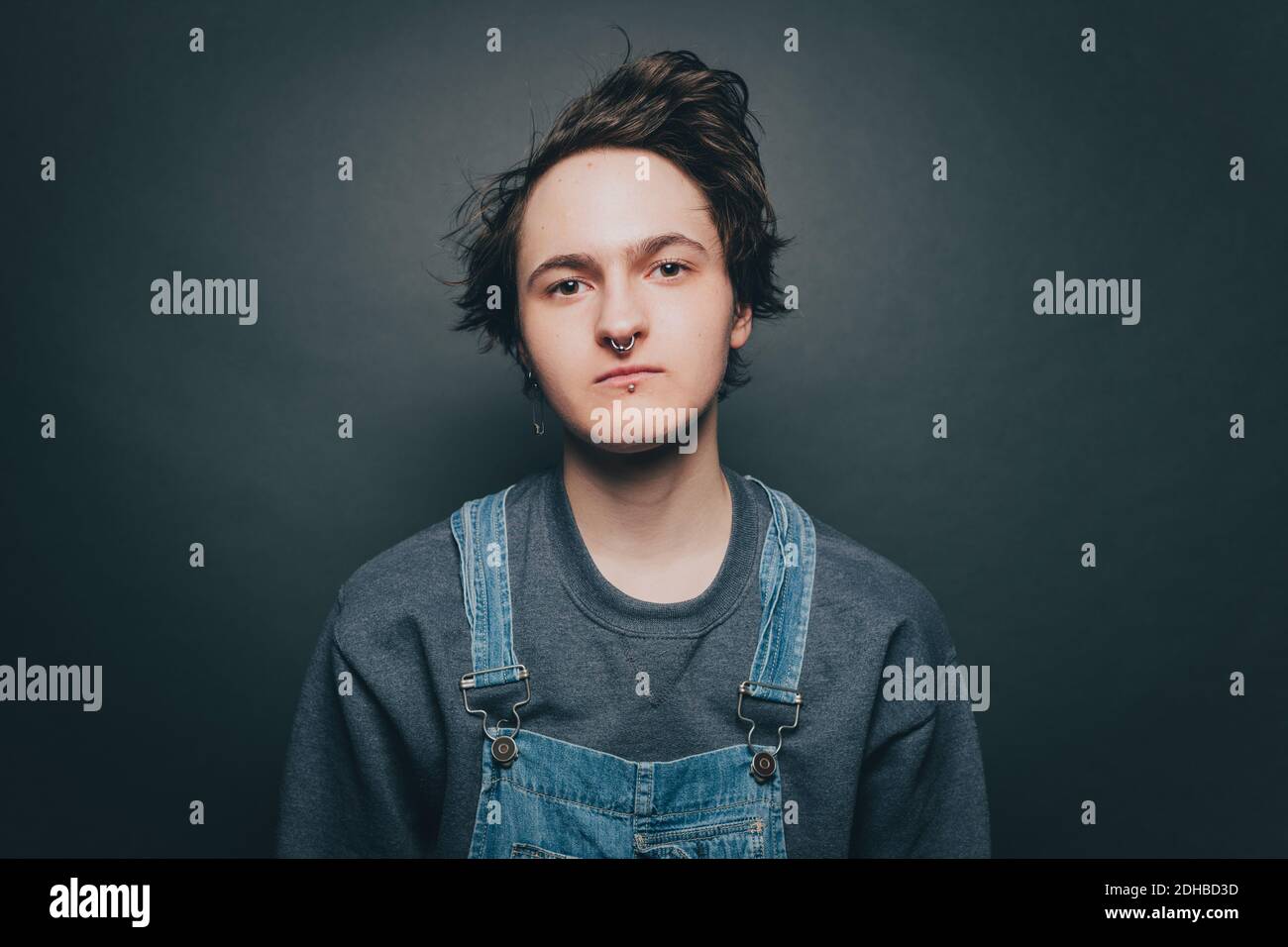 Porträt eines selbstbewussten jungen Mannes mit Overalls auf grauem Hintergrund Stockfoto