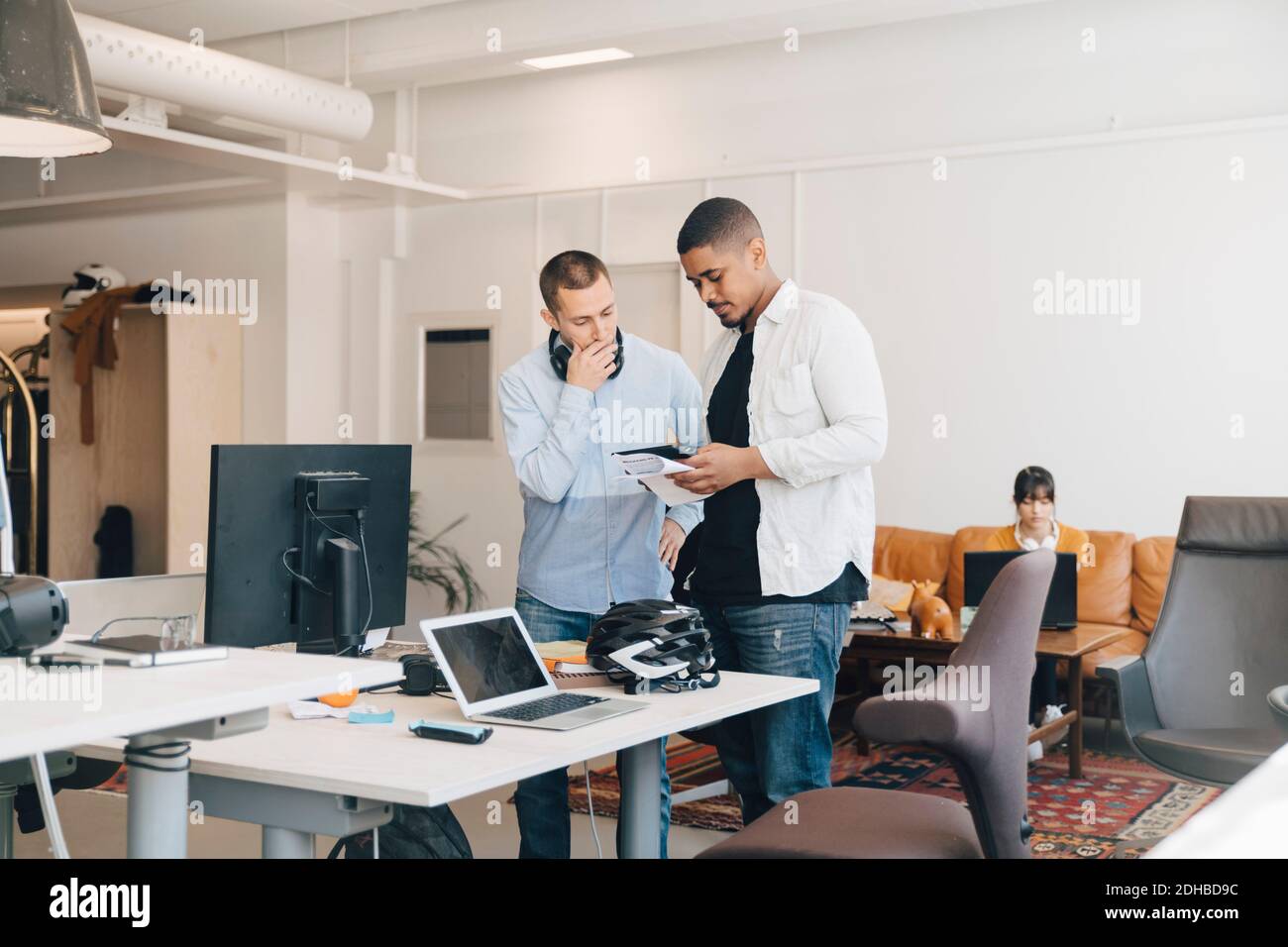 Männliche IT-Profis diskutieren über digitale Tablets, während sie dagegen stehen Wand im kreativen Büro Stockfoto