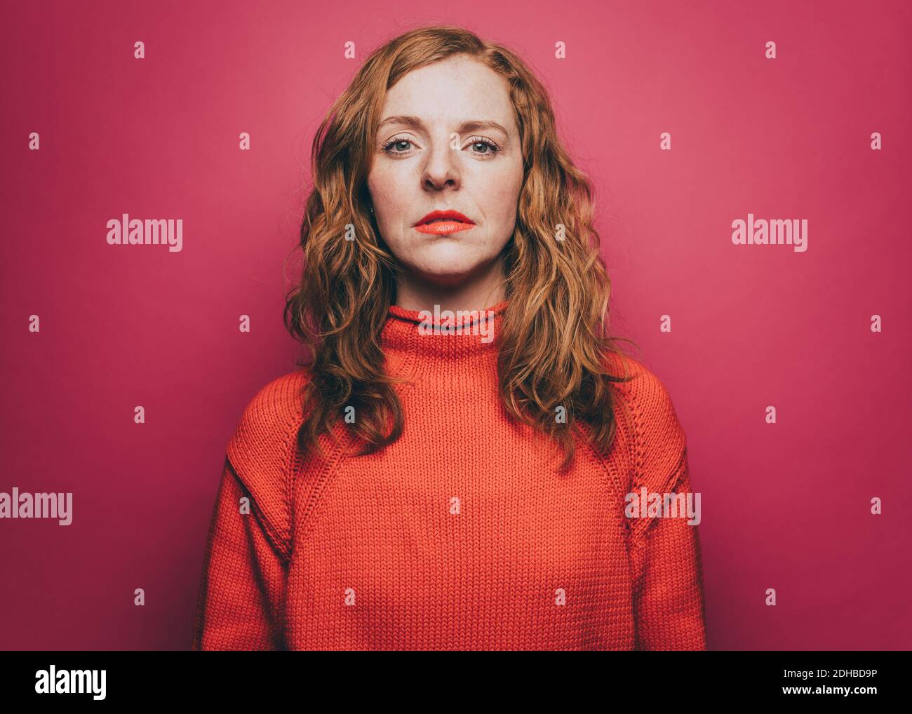 Porträt von selbstbewussten Frau in orange oben auf rosa Hintergrund Stockfoto
