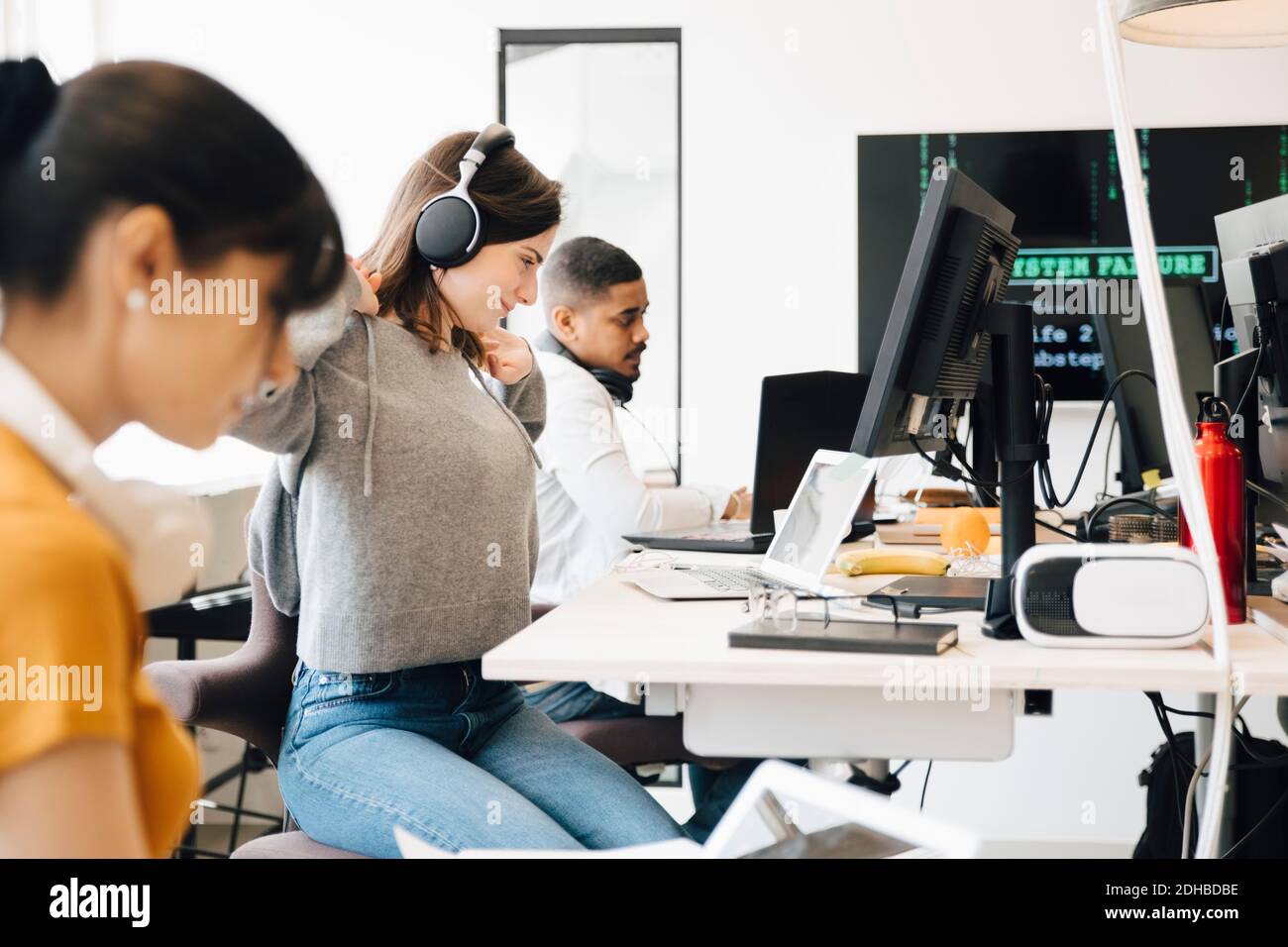 Seitenansicht von Computerprogrammierern, die am Schreibtisch arbeiten, während sie sitzen Im Büro Stockfoto