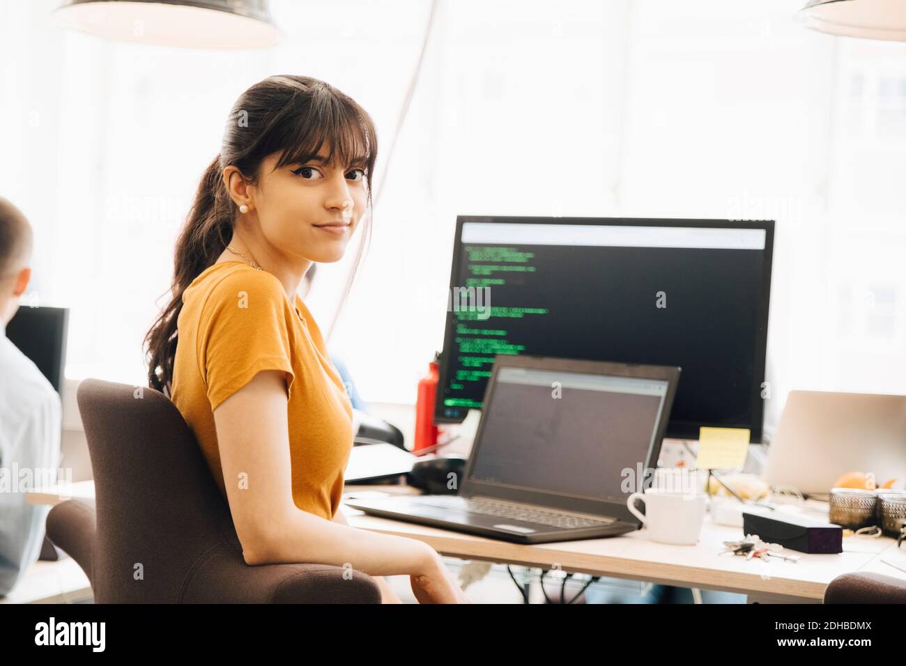 Portrait der weiblichen Programmierer mit Laptop, während am Schreibtisch sitzen Im Büro Stockfoto