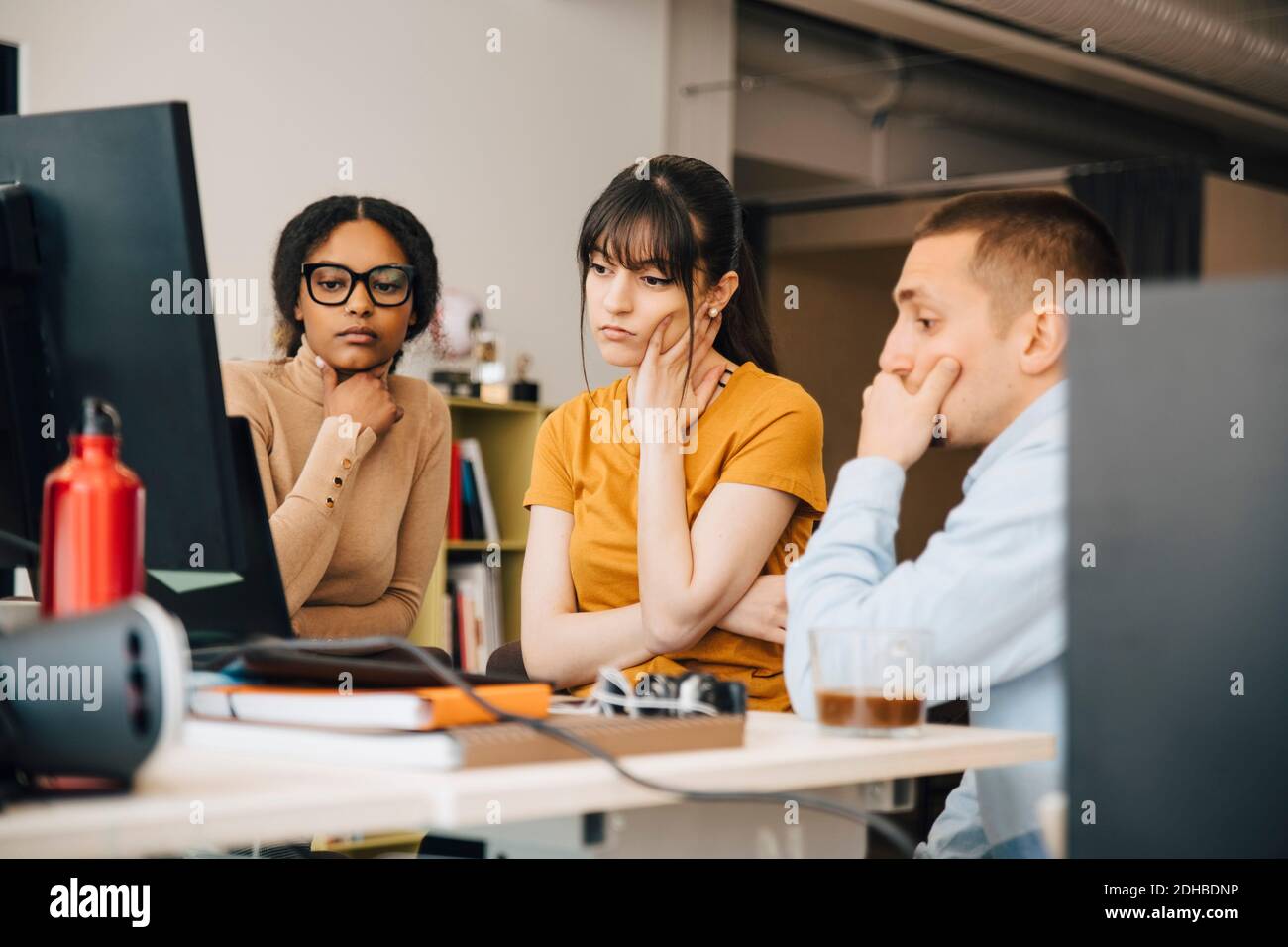 Fokussierte Computerprogrammierer, die Laptop betrachten, während sie zusammen an arbeiten Schreibtisch im Kreativbüro Stockfoto