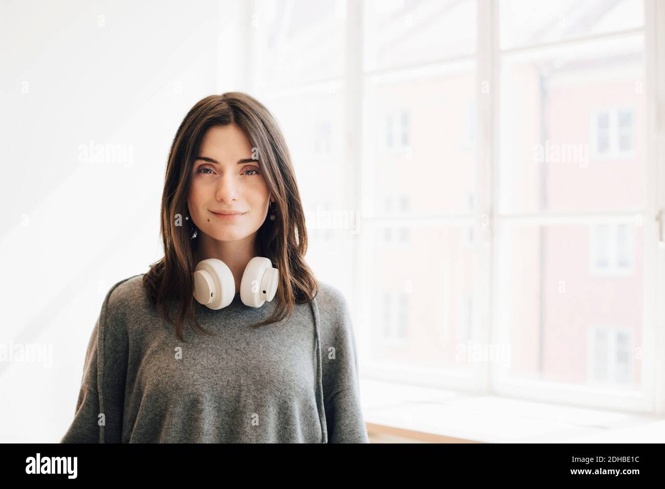 Portrait der weiblichen Computer-Programmierer mit Kopfhörer steht gegen Fenster Im Büro Stockfoto