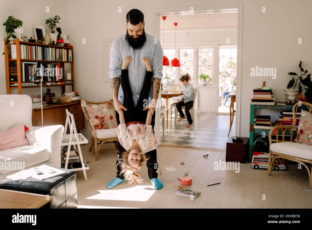 Verspielt Vater schwingt Mädchen, während im Wohnzimmer zu stehen Zu Hause Stockfoto
