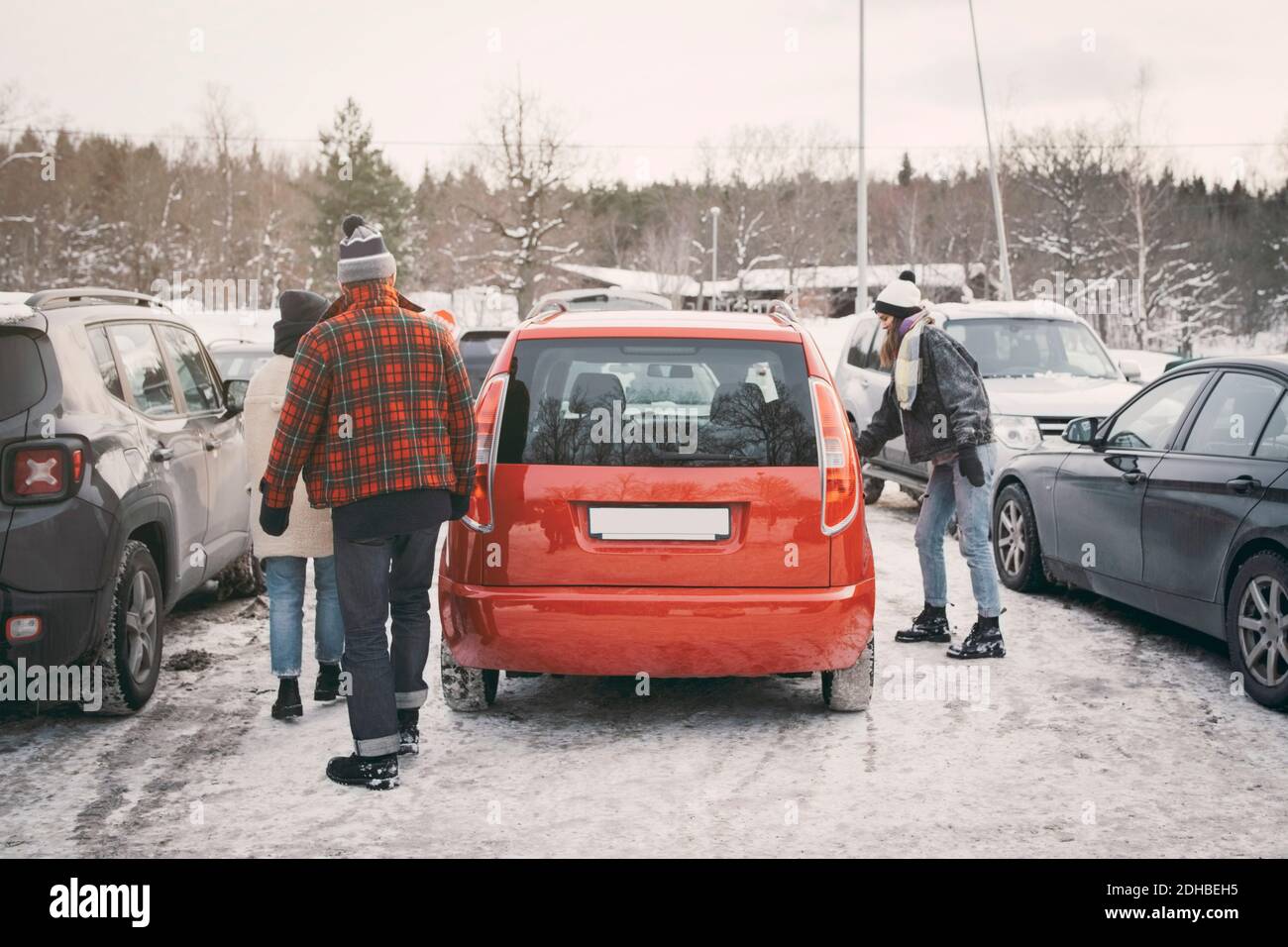 Freunde zu Fuß in Richtung Auto auf Parkplatz im Winter Stockfoto