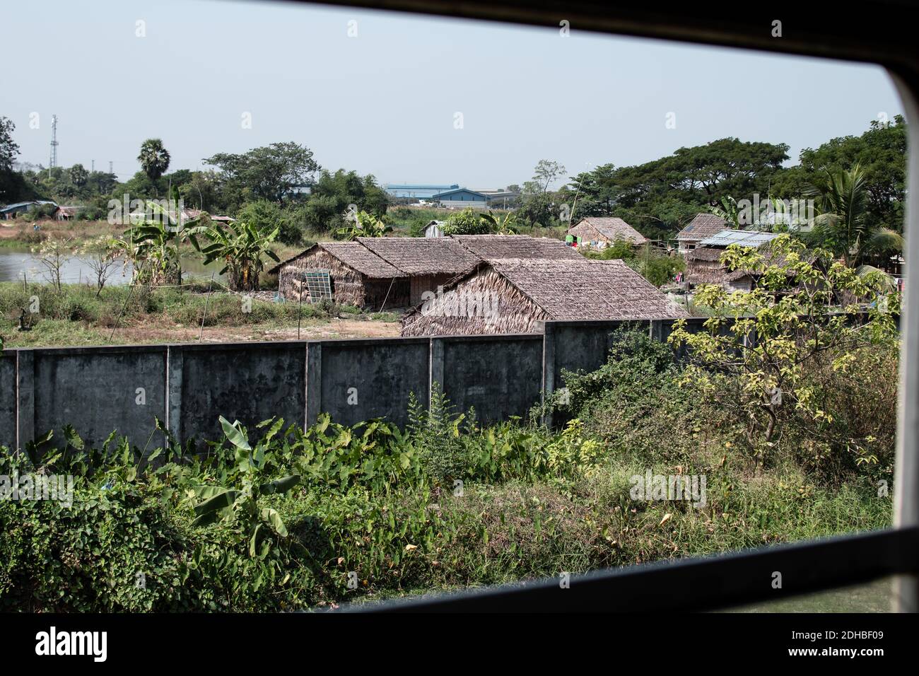 Blick aus einem Fenster aus dem sich bewegenden traditionellen Kreis Trainieren Sie über eine lokale Gesellschaft mit ein paar einfachen Holz Häuser Stockfoto
