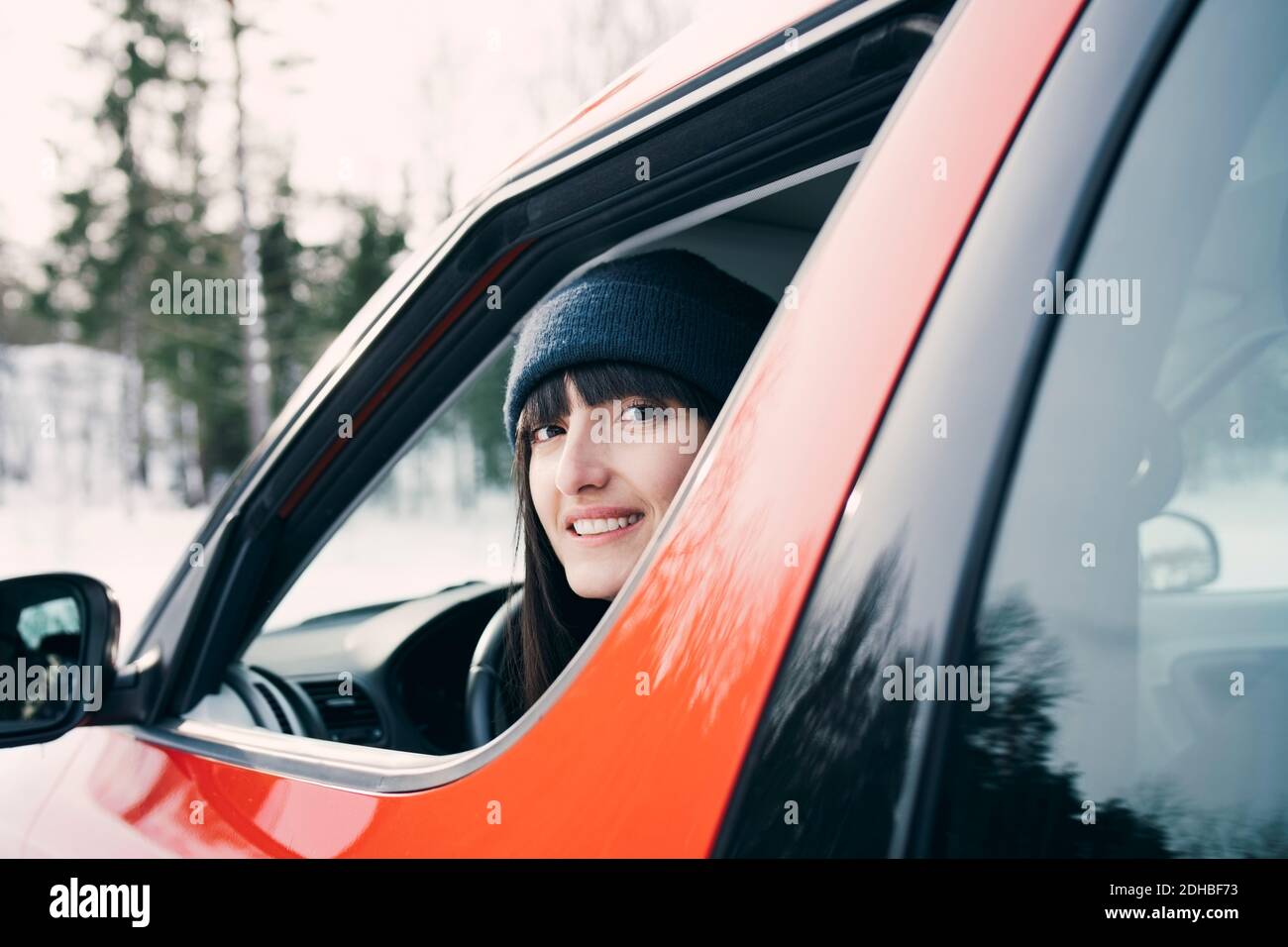 Porträt einer lächelnden Frau, die im roten Auto sitzt Stockfoto