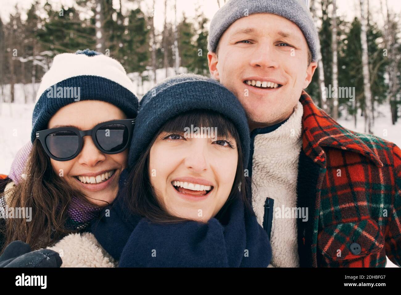 Portrait von fröhlichen Freunden tragen Strickmützen im Park während Winter Stockfoto