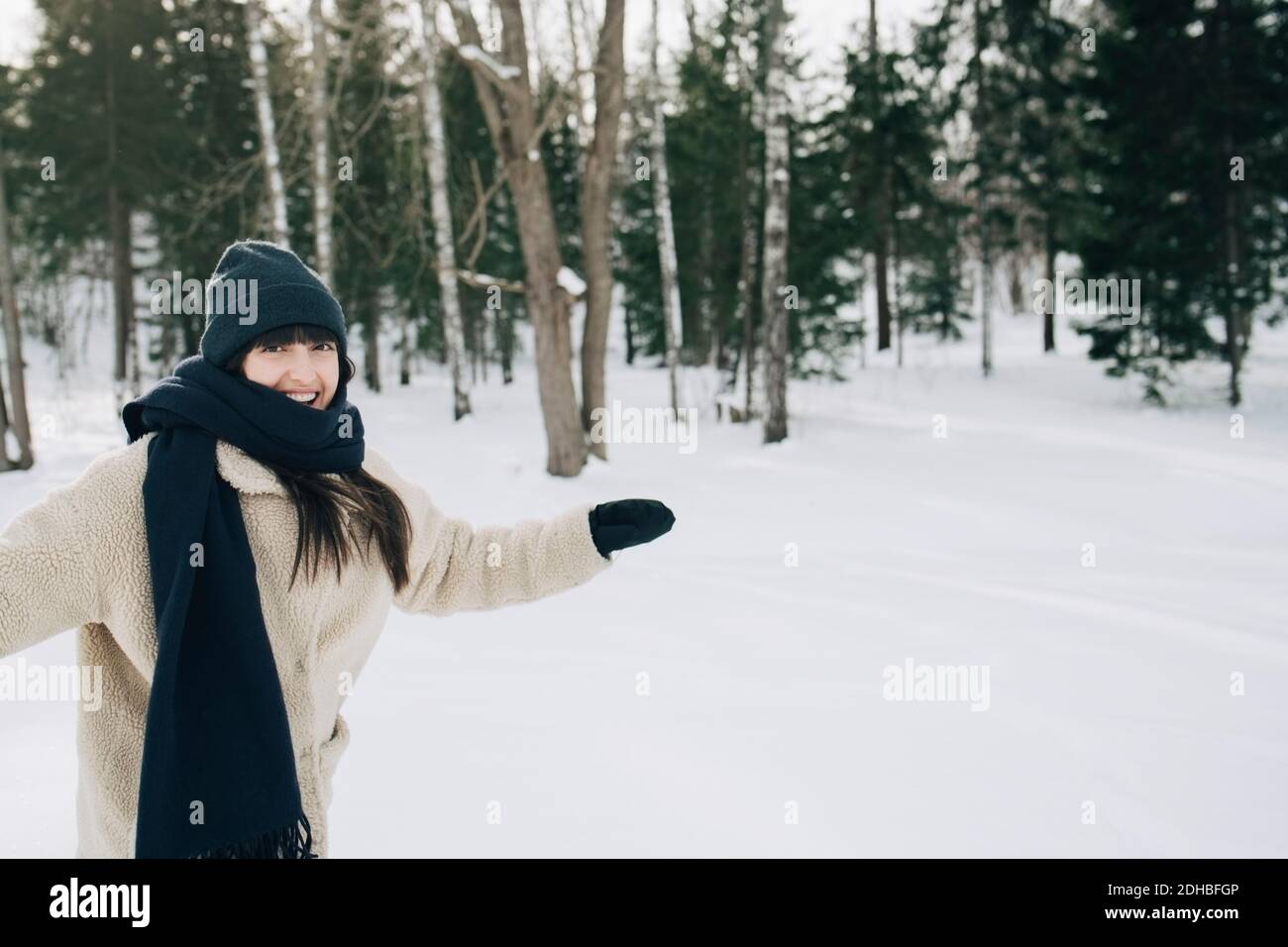 Porträt einer glücklichen Frau, die mit ausgestreckten Armen auf Schnee steht Überdachte Landschaft Stockfoto