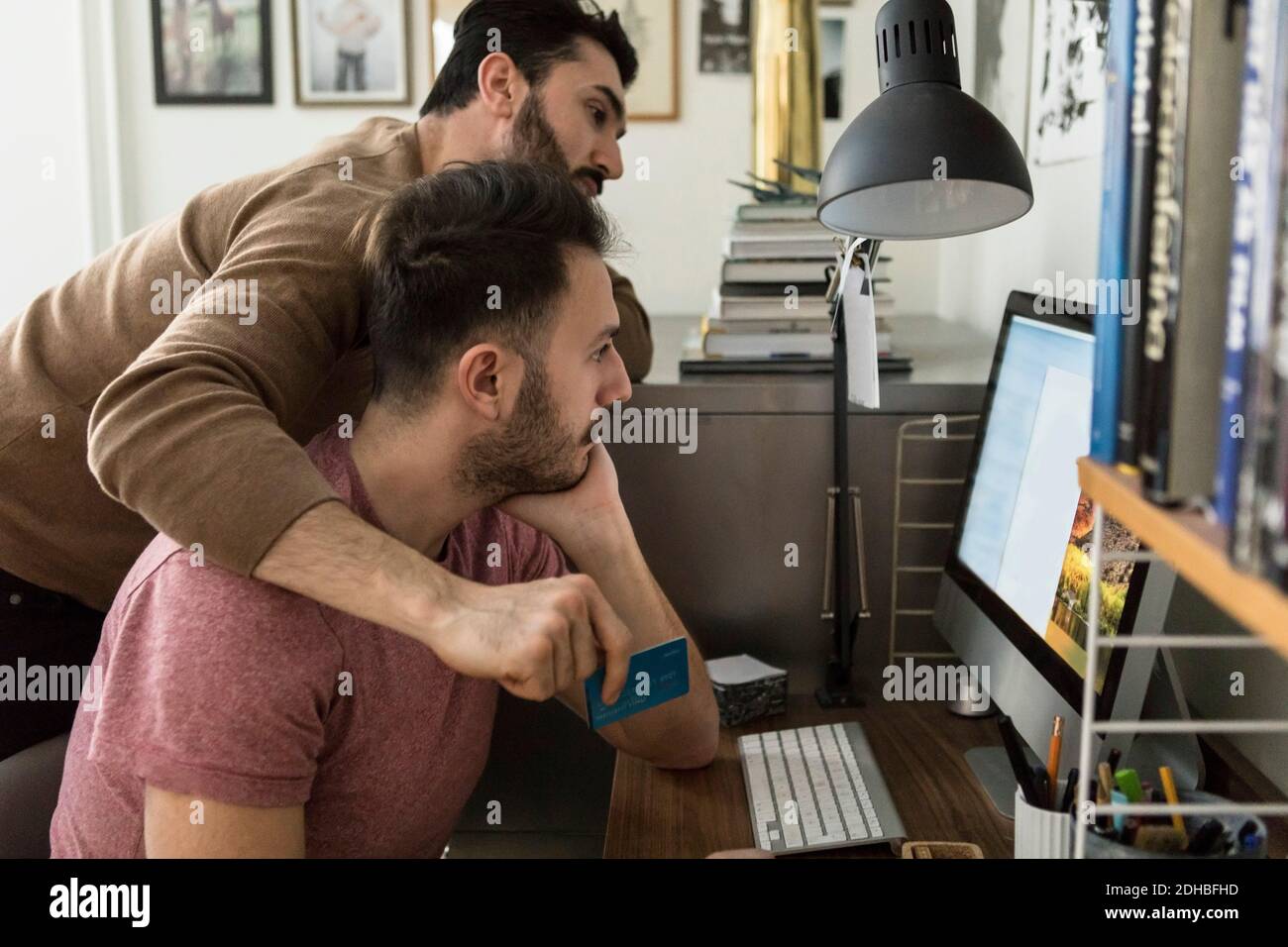 Homosexuell paar Online-Shopping durch Kreditkarte auf Computer bei Zu Hause Stockfoto