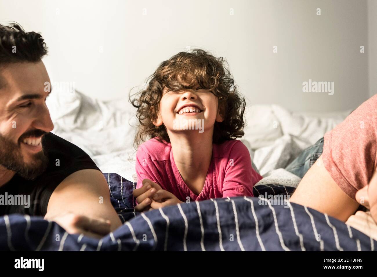 Väter schauen auf fröhliche Tochter spielen auf dem Bett zu Hause Stockfoto
