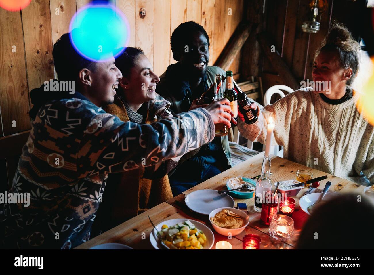 Blick auf glückliche Männer und Freunde, die Bier toasten Flaschen in der Blockhütte Stockfoto