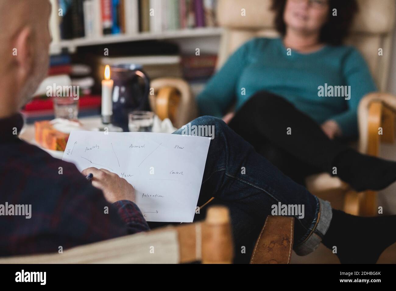 Männlicher Therapeut, der Papier analysiert, während er mit dem Patienten zu Hause sitzt Büro Stockfoto