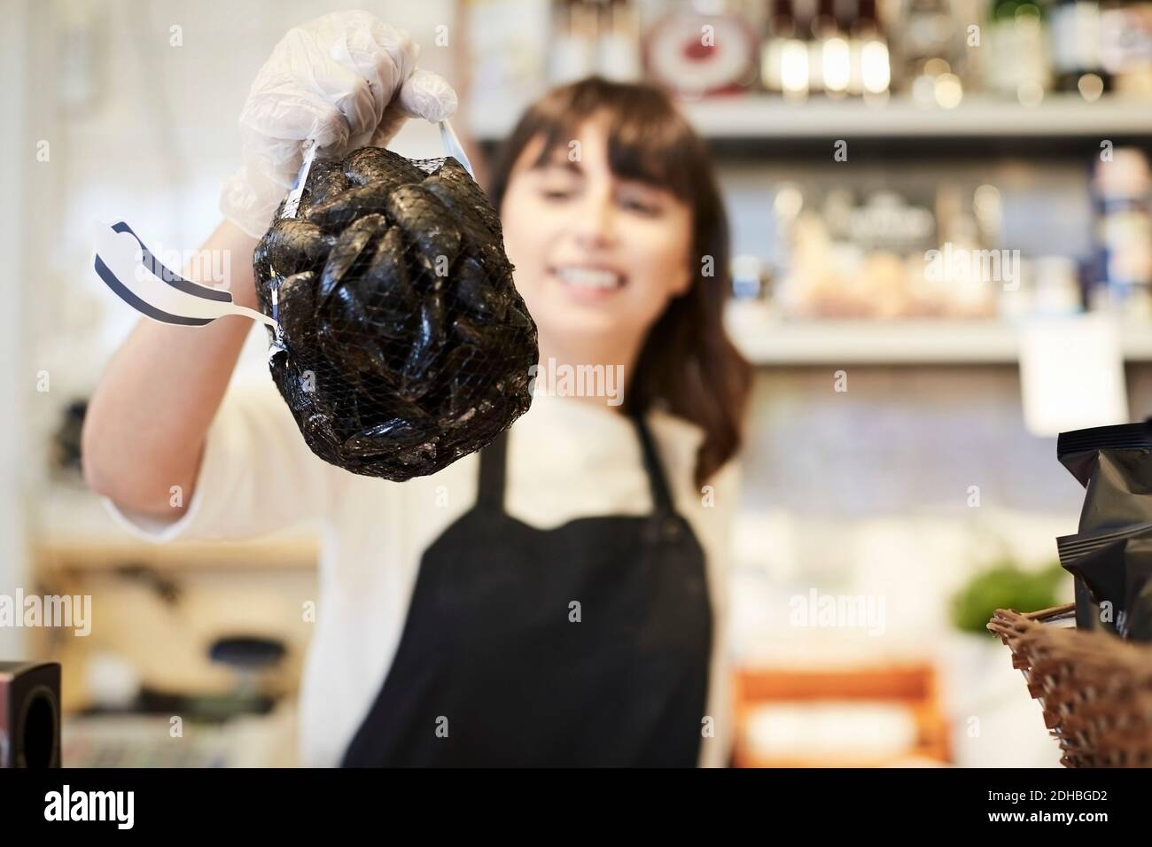 Lächelnde Besitzerin, die Muscheln im Laden hält Stockfoto