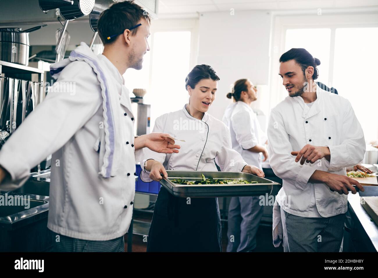 Männliche und weibliche Köche diskutieren über Essen in Backblech In der kommerziellen Küche Stockfoto