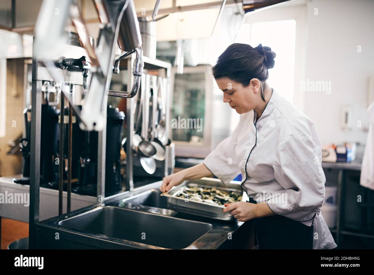 Mittlere Erwachsene weibliche Köchin, die Essen in der kommerziellen Küche zubereitet Stockfoto