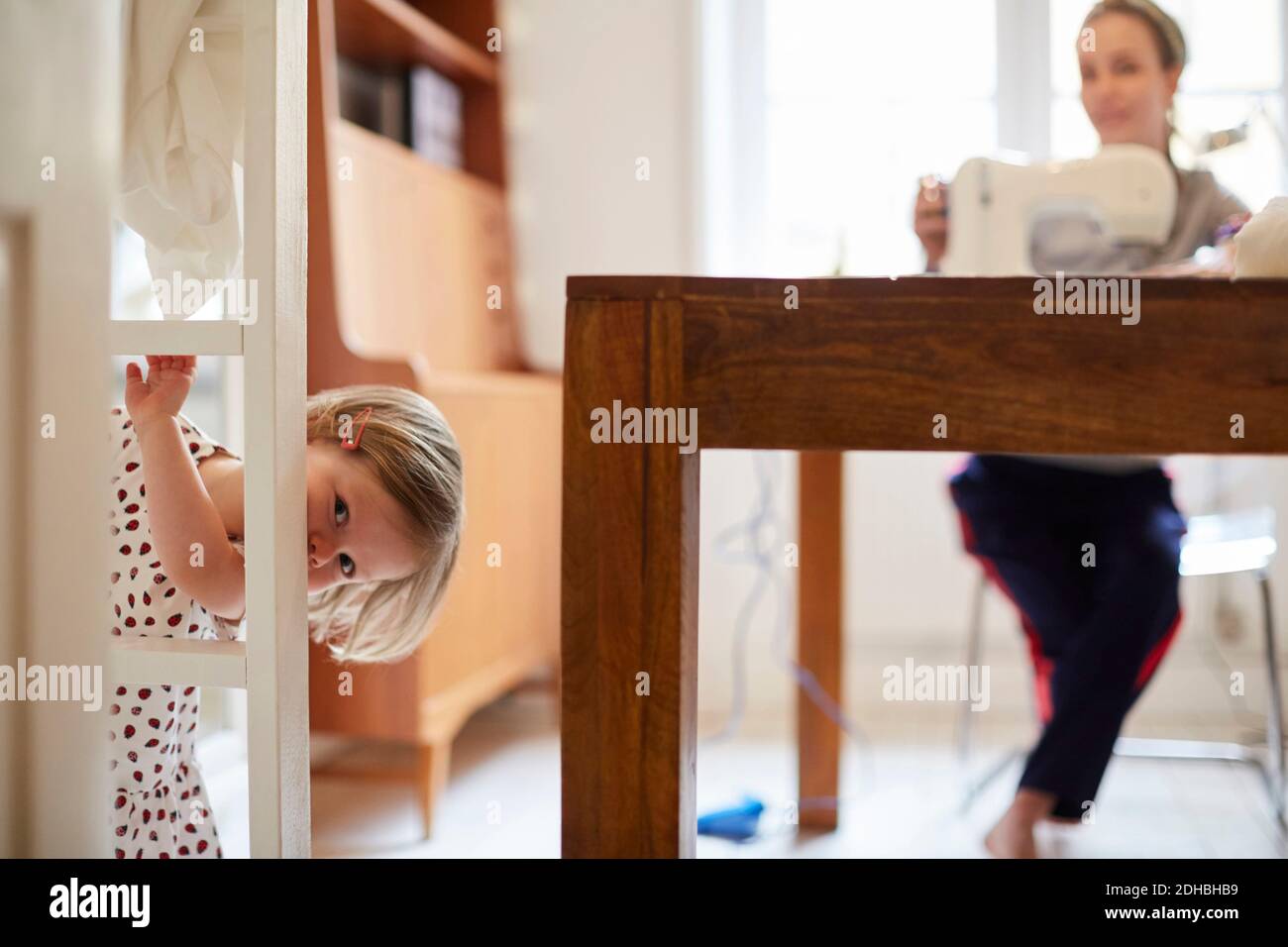 Mädchen suchen, während hinter der Tür mit Mutter arbeiten in stehen Hintergrund Stockfoto