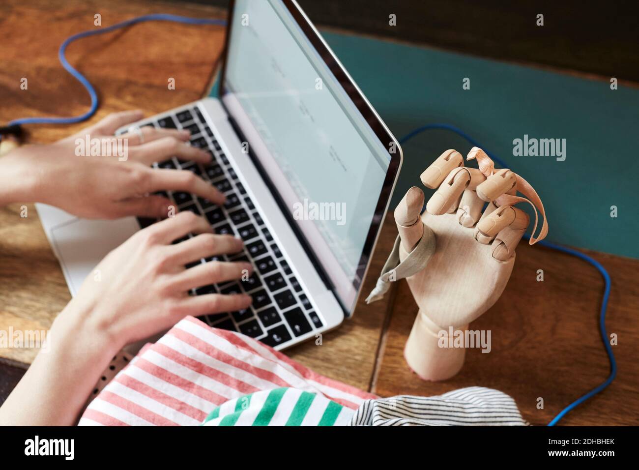 Zugeschnittenes Bild von Podcaster Eingabe auf Laptop von Hand Schaufensterpuppe Mit Haarelastik am Tisch Stockfoto