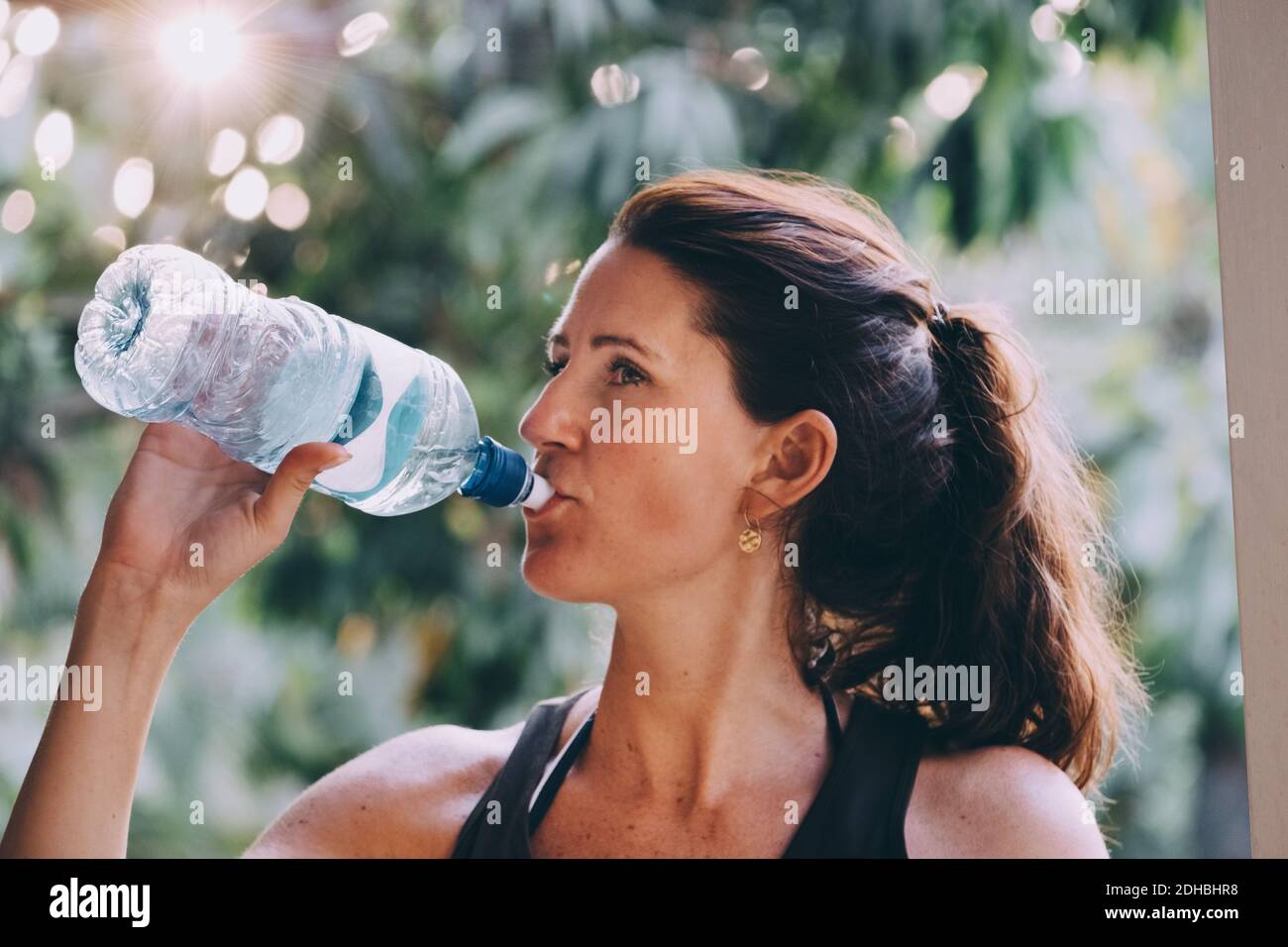 Reife Frau, die Wasser aus der Flasche am Strand trinkt Stockfoto