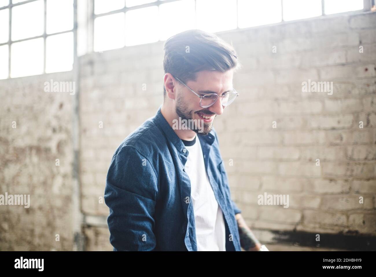 Lächelnder bärtiger Geschäftsmann trägt smart casual während der Arbeit in IHM Fest Stockfoto