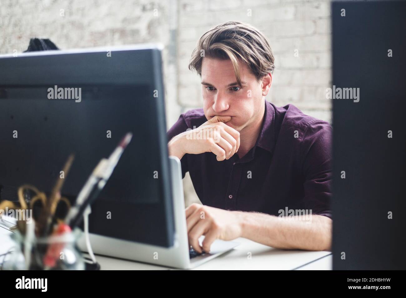Besorgt professionelle Hacker Blick auf Laptop in kreativen Büro Stockfoto