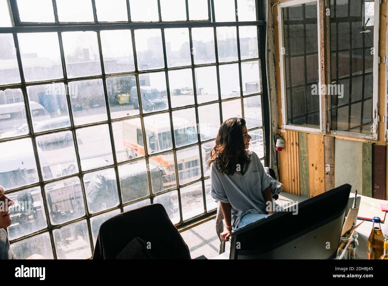 Junge Geschäftsfrau, die auf einem Stuhl gegen das Fenster im Konferenzraum sitzt Am kreativen Arbeitsplatz Stockfoto