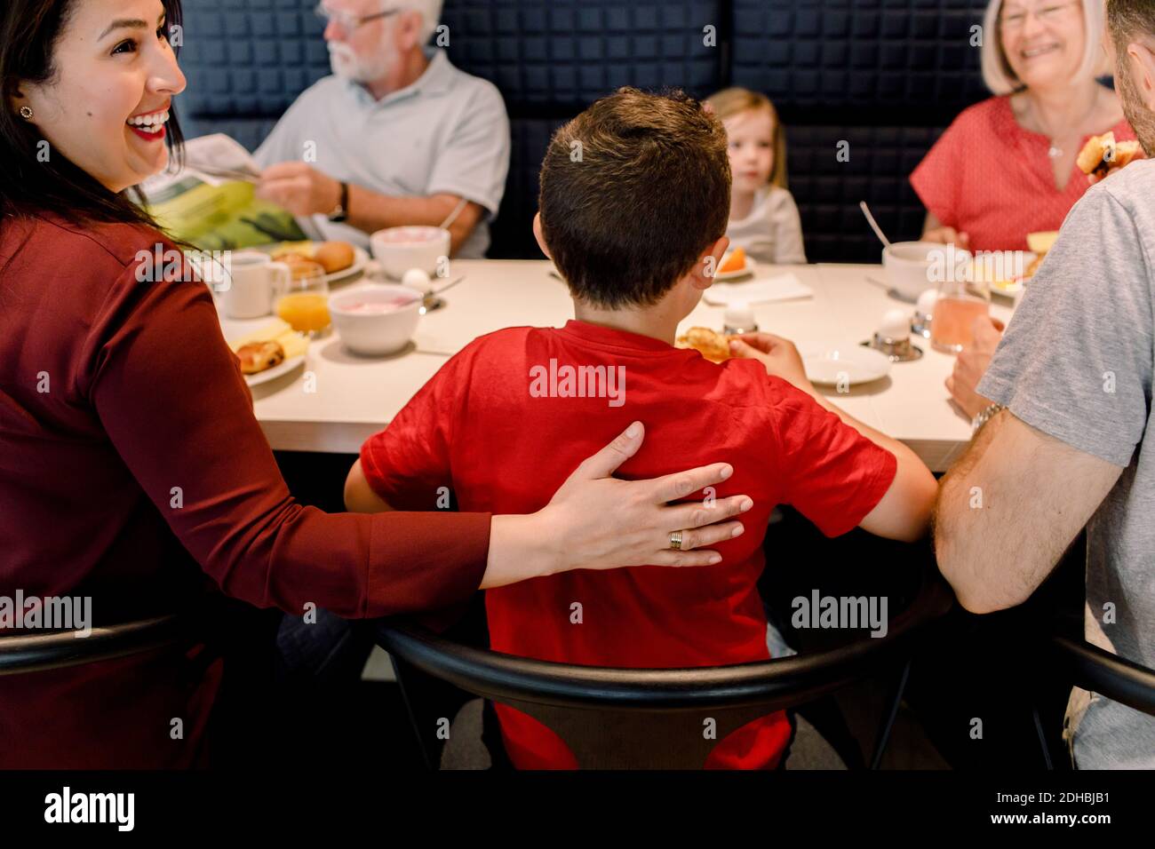 Lächelnde Frau schaut weg, während die Familie beim Frühstück sitzt Restaurant Stockfoto