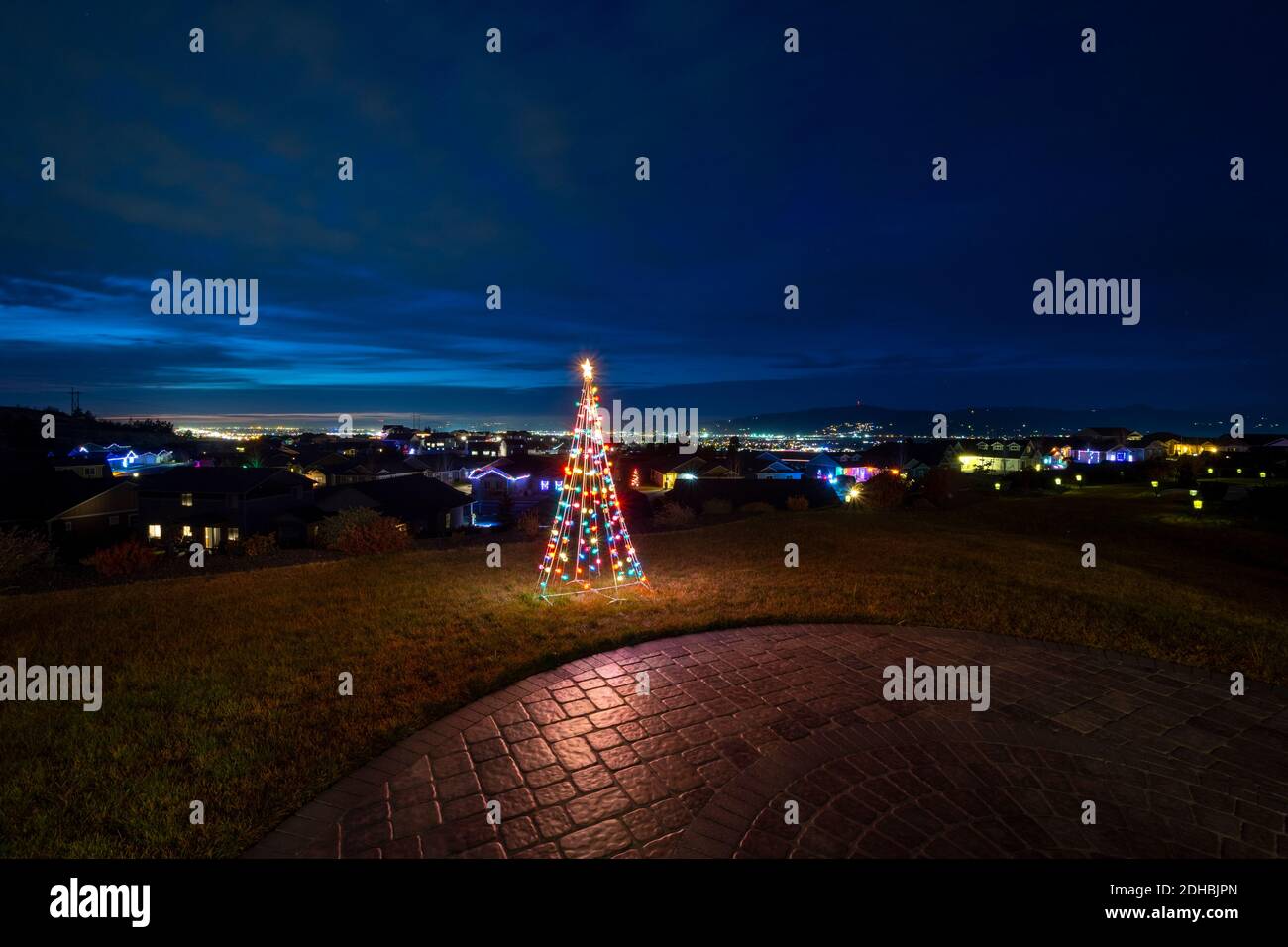 Ein beleuchtetes Weihnachtsschmuck sitzt auf einem Hügel Terrasse mit Blick auf das Spokane Valley und die Innenstadt in Washington State, USA Stockfoto