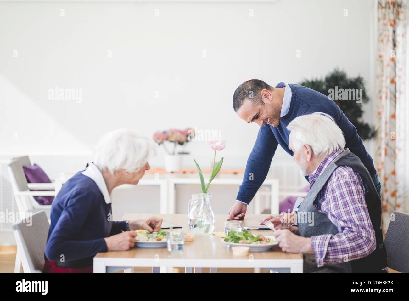 Sohn, der Mutter und Vater beim Mittagessen Handy zeigt Am Tisch im Pflegeheim Stockfoto