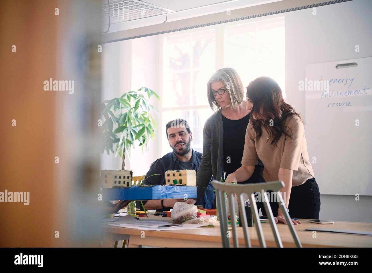 Multi-ethnische männliche und weibliche Ingenieure diskutieren über Architekturmodell bei Tisch während der Besprechung im Büro Stockfoto