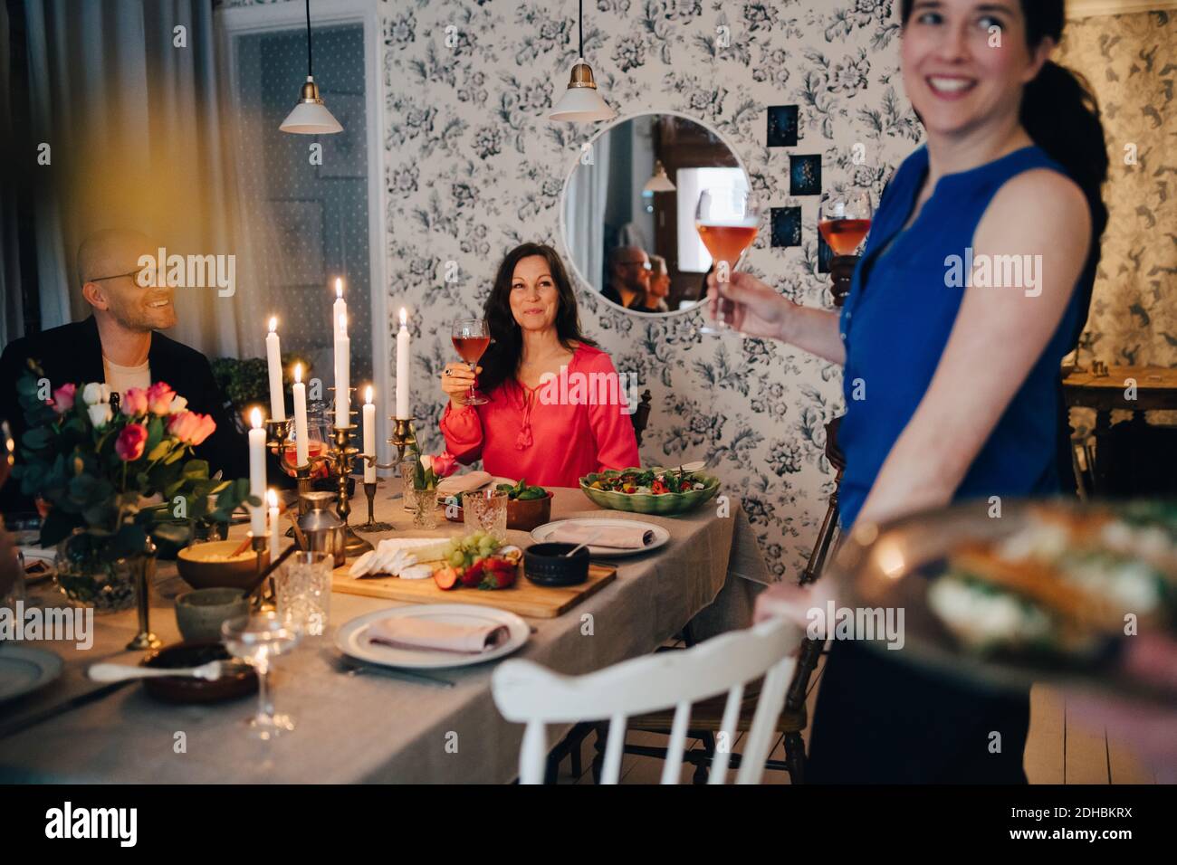 Frau genießt Getränke mit Freunden am Esstisch in Party Stockfoto