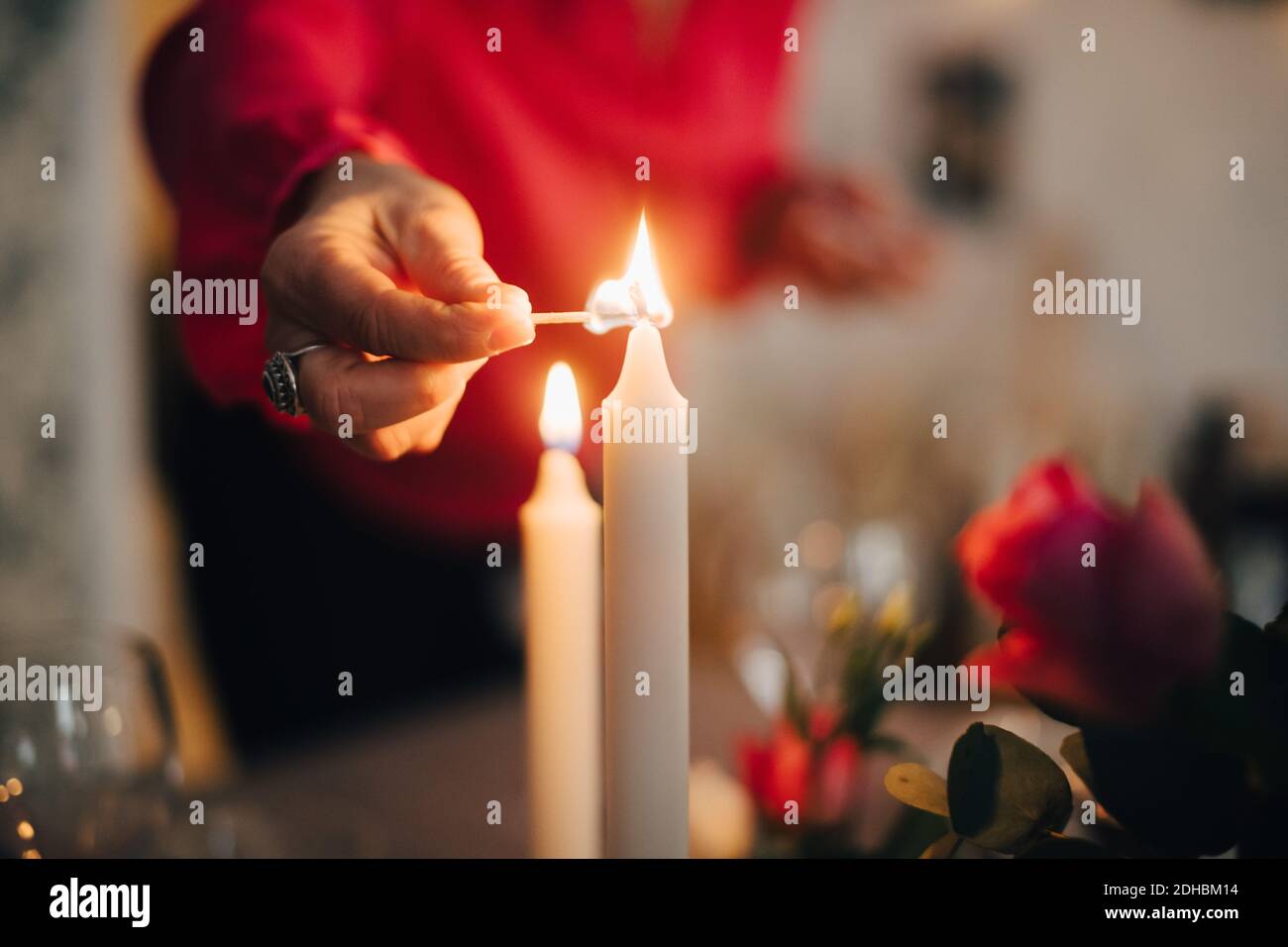 Mittelteil der reifen Frau zündet Kerze auf Esstisch in Party zu Hause Stockfoto